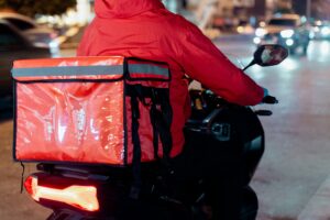 A imagem mostra um entregador de delivery em uma moto.